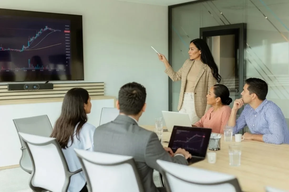 A consultant presenting a performance chart to colleagues in a boardroom